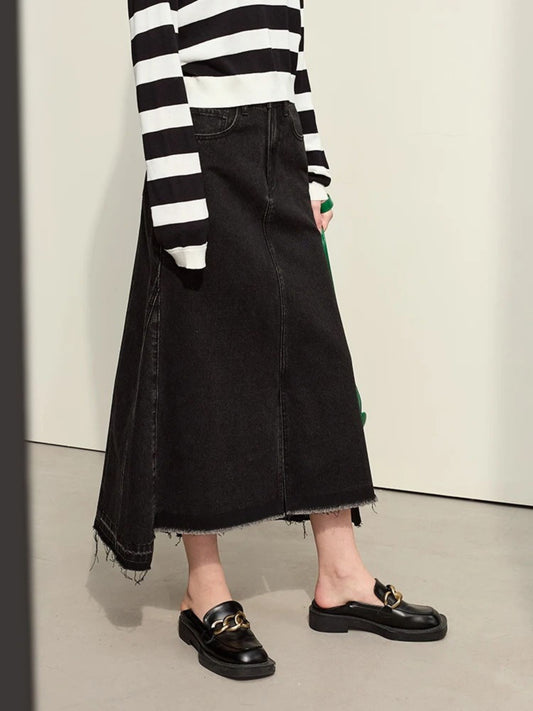 Side view of black denim midi skirt with slit, paired with black-and-white striped sweater and black loafers