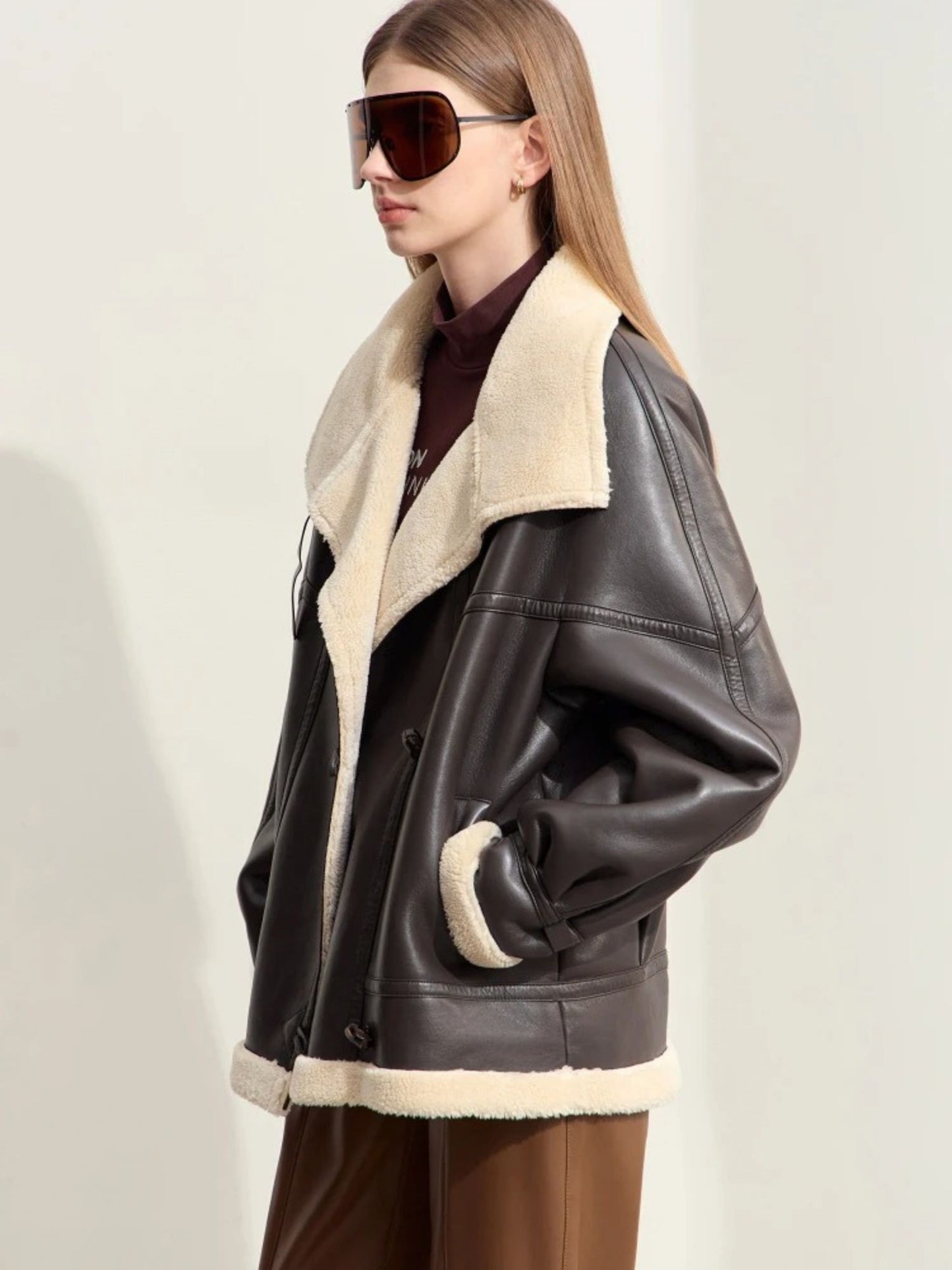 Close-up of model in aviator jacket and oversized sunglasses, highlighting shearling details