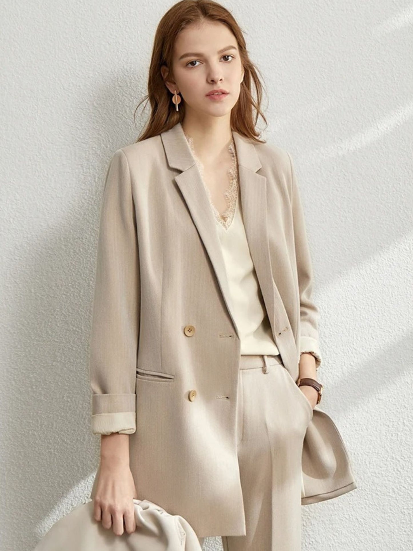 Model in light beige blazer and pants set, styled with ivory camisole and soft makeup