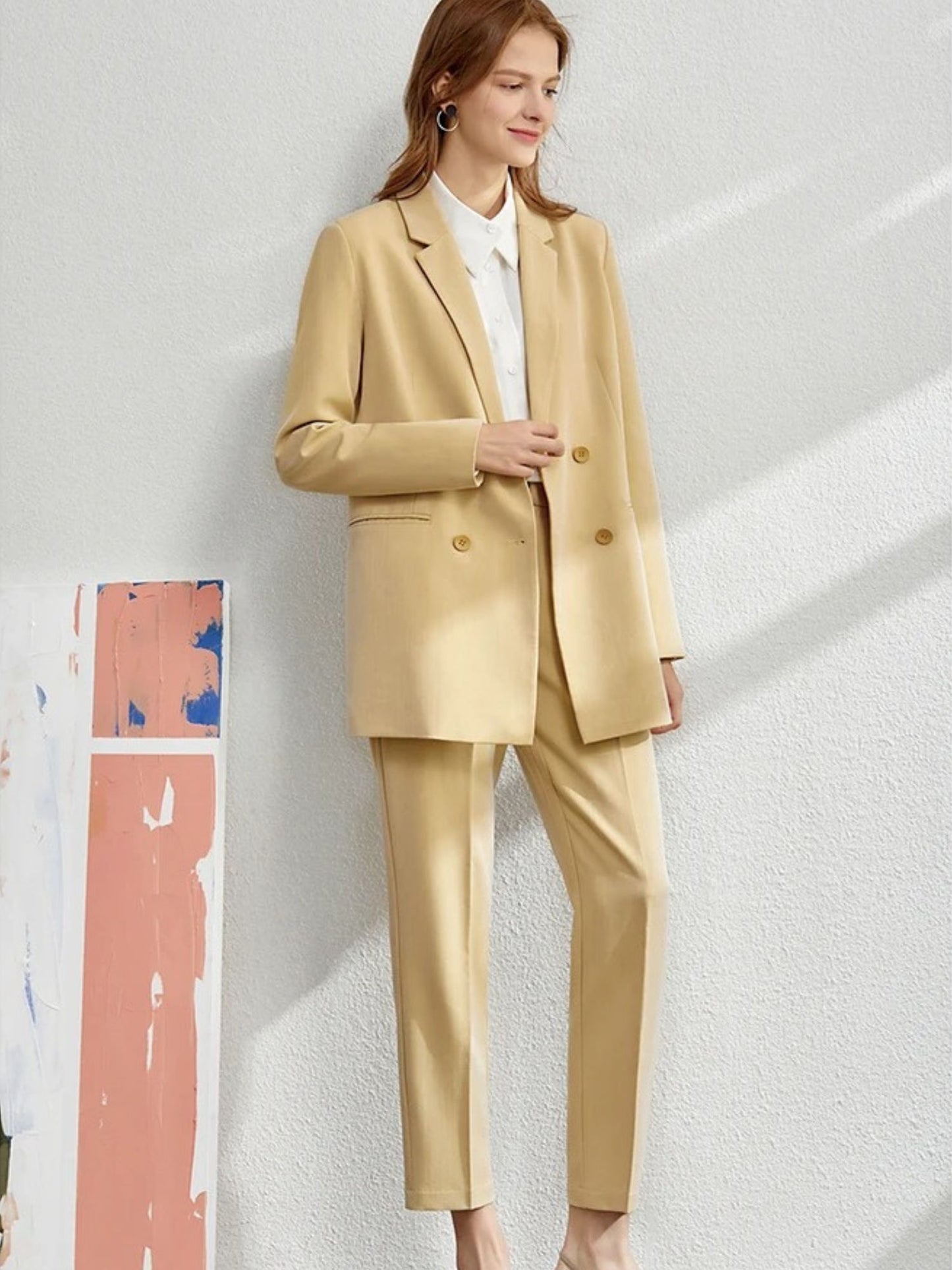Beige blazer and trousers paired with white pointed heels and handbag