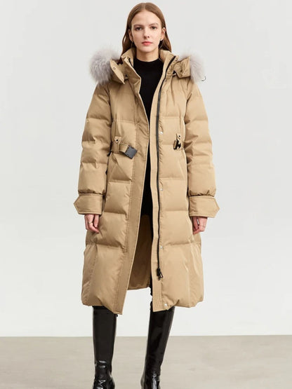 Front view of the beige version of the same coat. It’s belted at the waist and worn with black tights and boots. The model stands with arms relaxed at sides