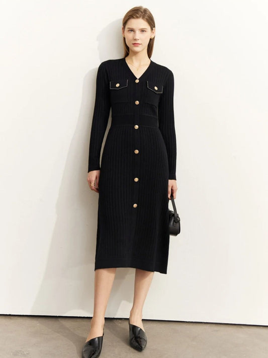 Women's black ribbed knit midi dress with long sleeves, gold button-front closure, and chest pockets. Model holding a black handbag