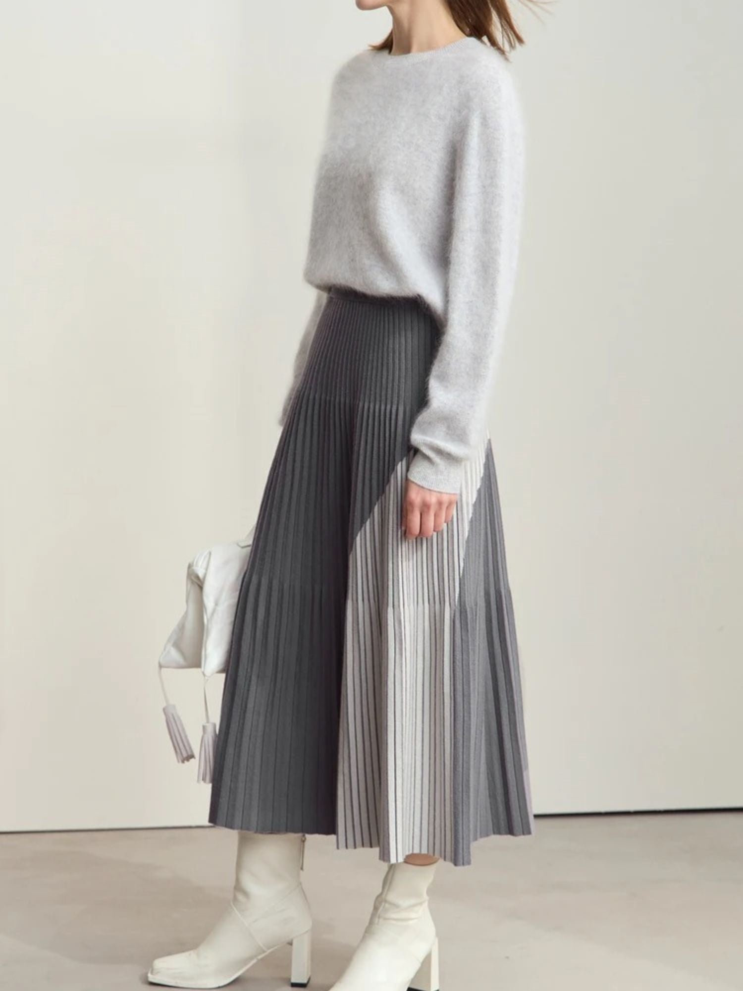 Side view of gray pleated midi skirt with color-block panels in light and dark gray