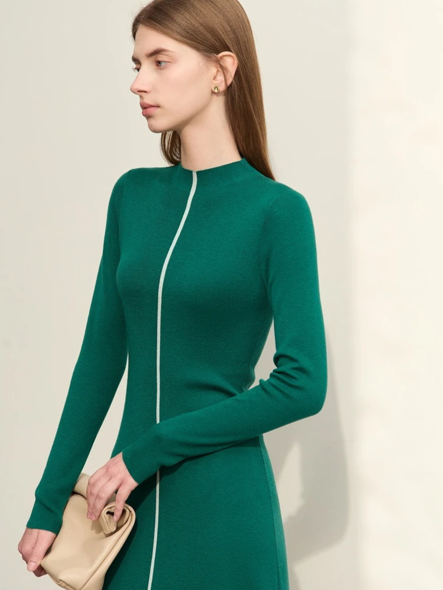 Green long-sleeve midi dress with front zipper and fitted silhouette, model holding beige handbag
