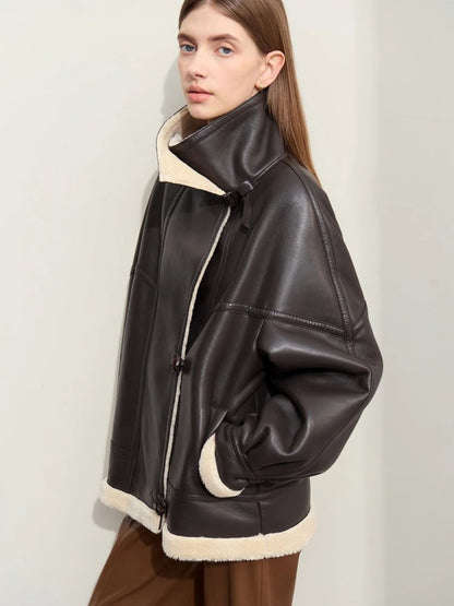 Side profile view of the model showing the oversized silhouette of the jacket. She holds her hands casually in the jacket’s side pockets, and the shearling lining is visible at the collar and hem