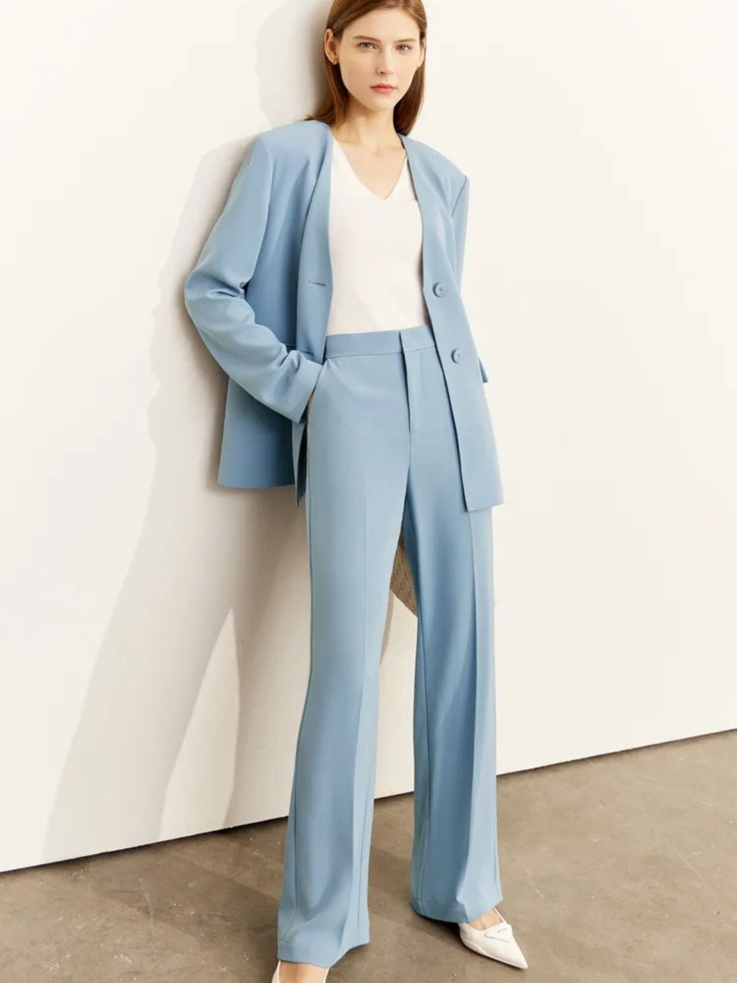 Woman wearing a light blue suit with a white top against a plain background