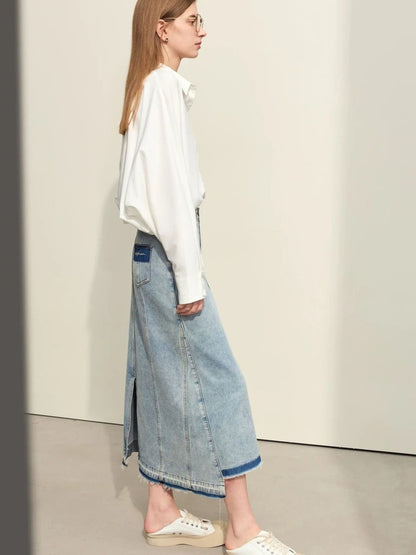 Side view of light blue denim skirt with front slit, paired with oversized white sweater and beige flats