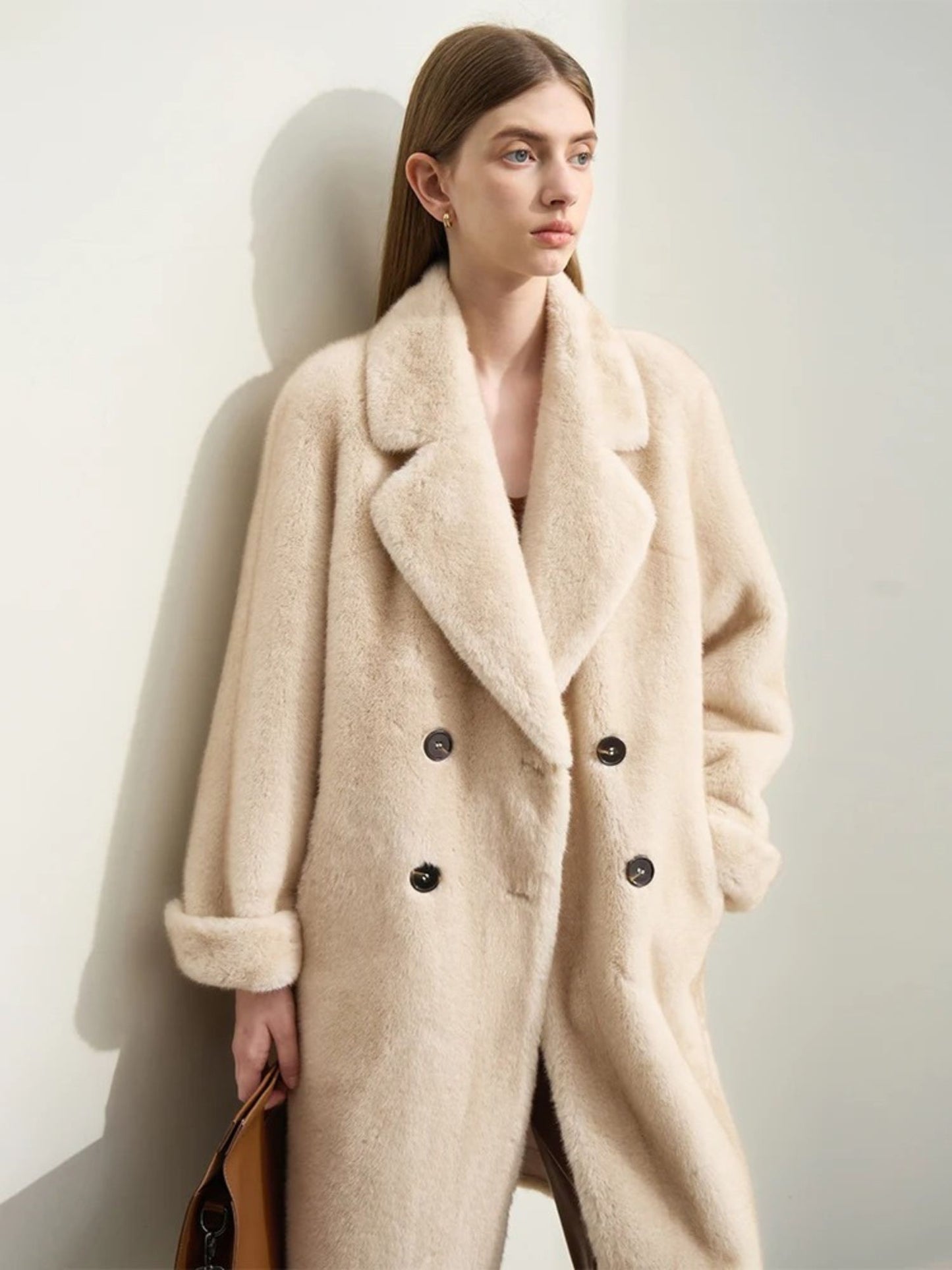 Side angle of the model in the same outfit. She is looking slightly upward, hands in coat pockets. The volume and softness of the coat are emphasized from this angle