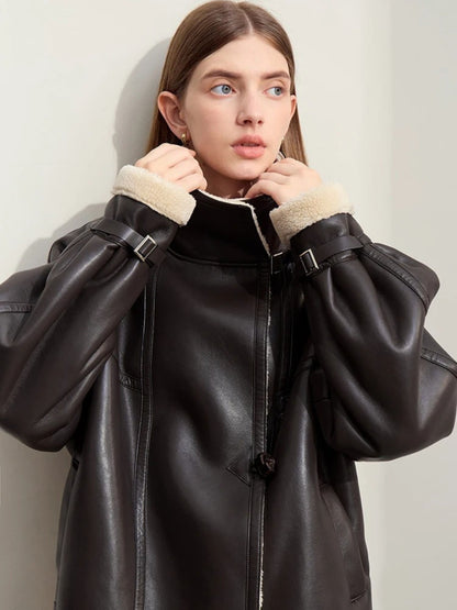 Close-up frontal shot of the model with the collar pulled up around her face, showcasing the cream shearling interior and high-neck warmth. She looks forward with a neutral expression