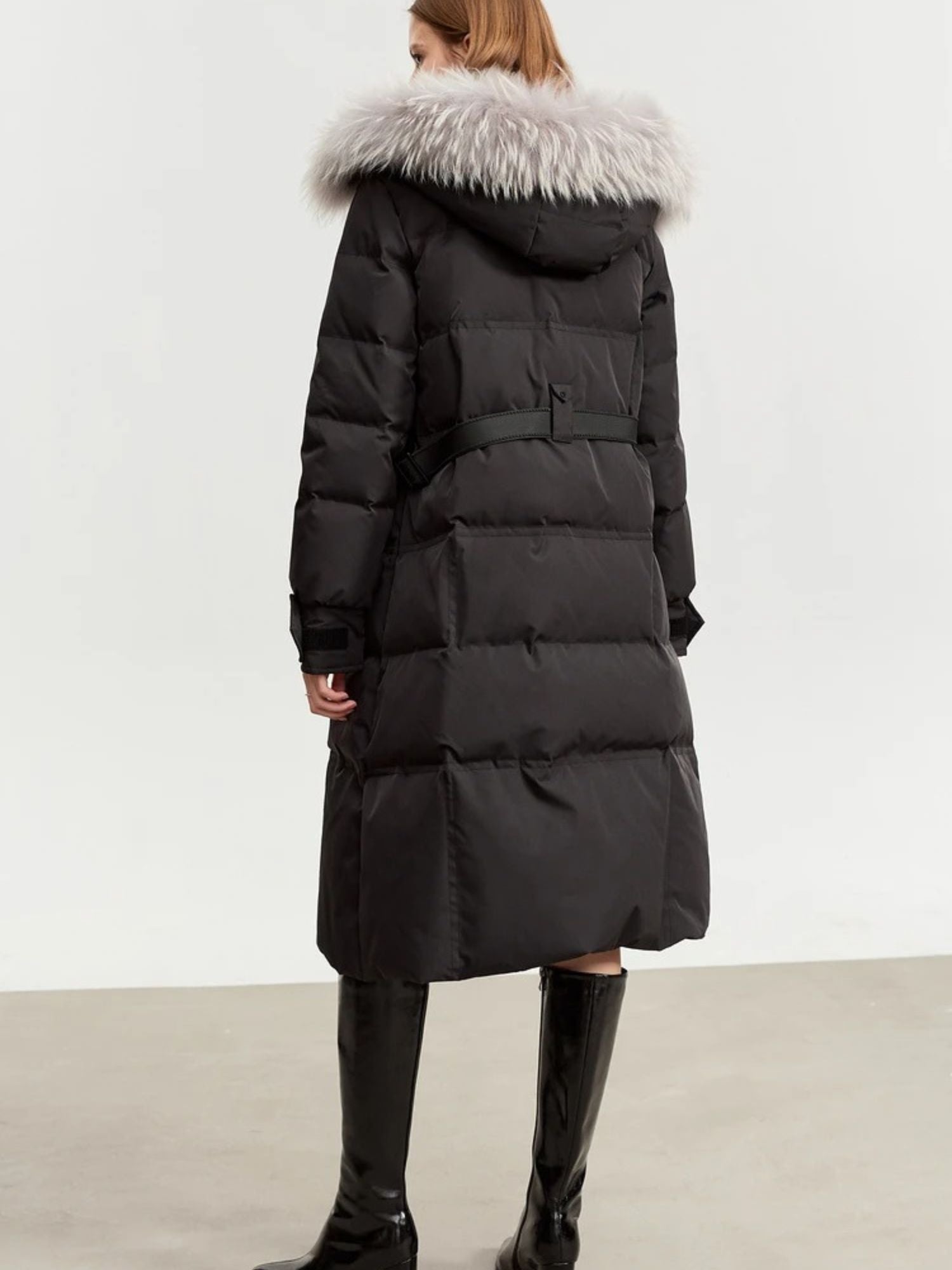 Rear view of the black coat, showing the hood and straight-cut length down to the calves