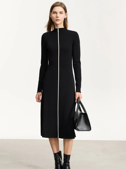 Black long-sleeve midi dress with front zipper, fitted shape, crew neckline, styled with black ankle boots and black handbag