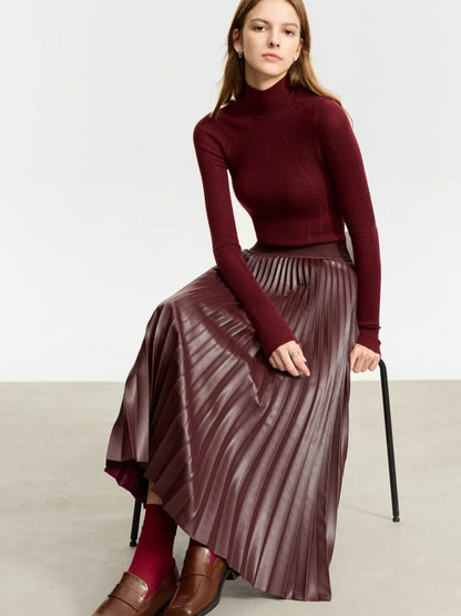 Seated front view of burgundy faux leather pleated midi skirt paired with matching burgundy top