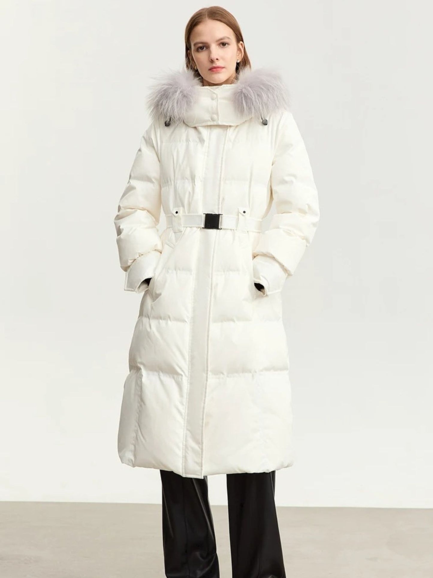 Front view of the coat in white. The model wears the coat fully zipped and styled simply with black pants and boots