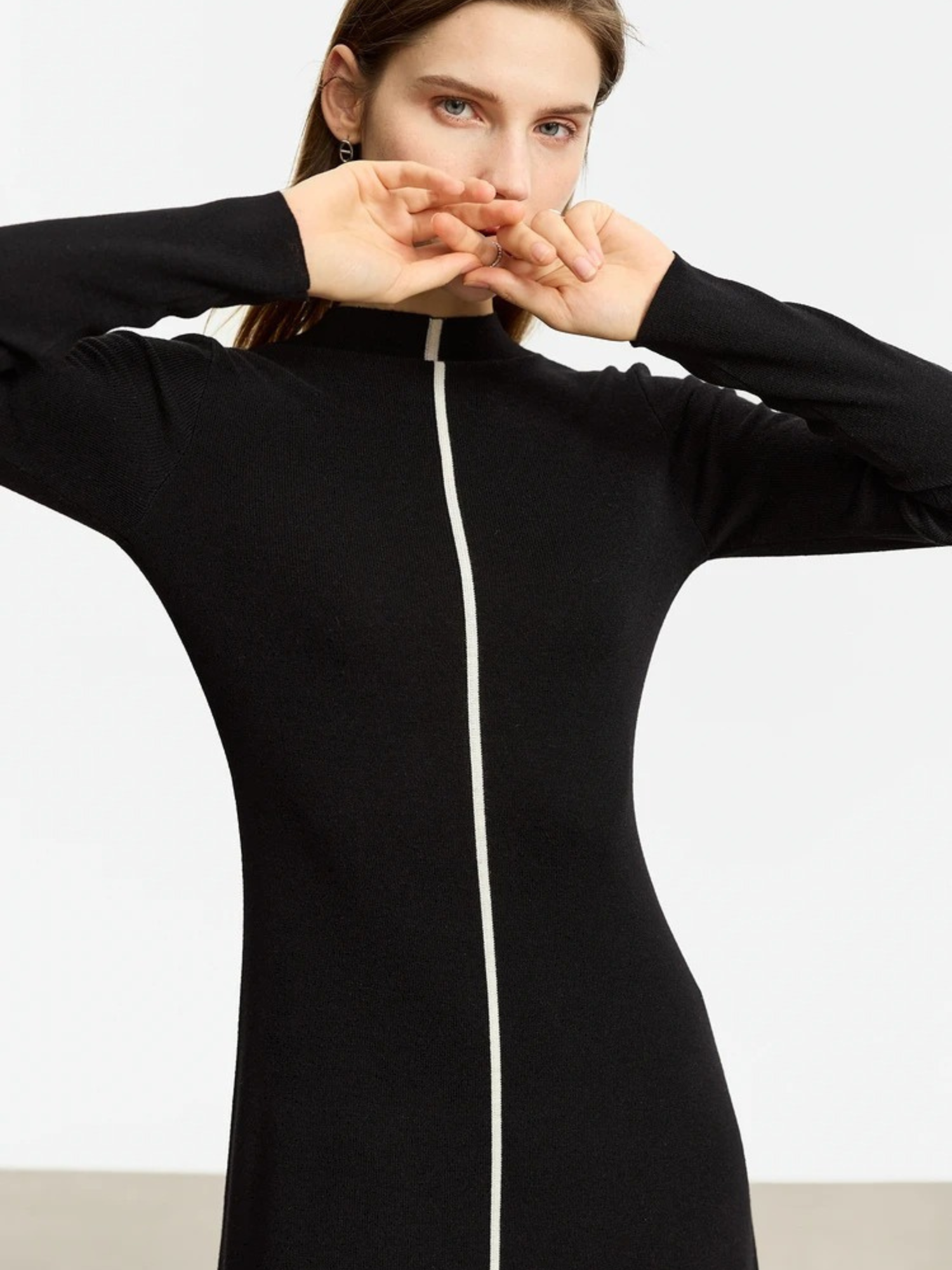 Model in black long-sleeve midi dress with front zipper, stretching arms forward to show fabric stretch and fit