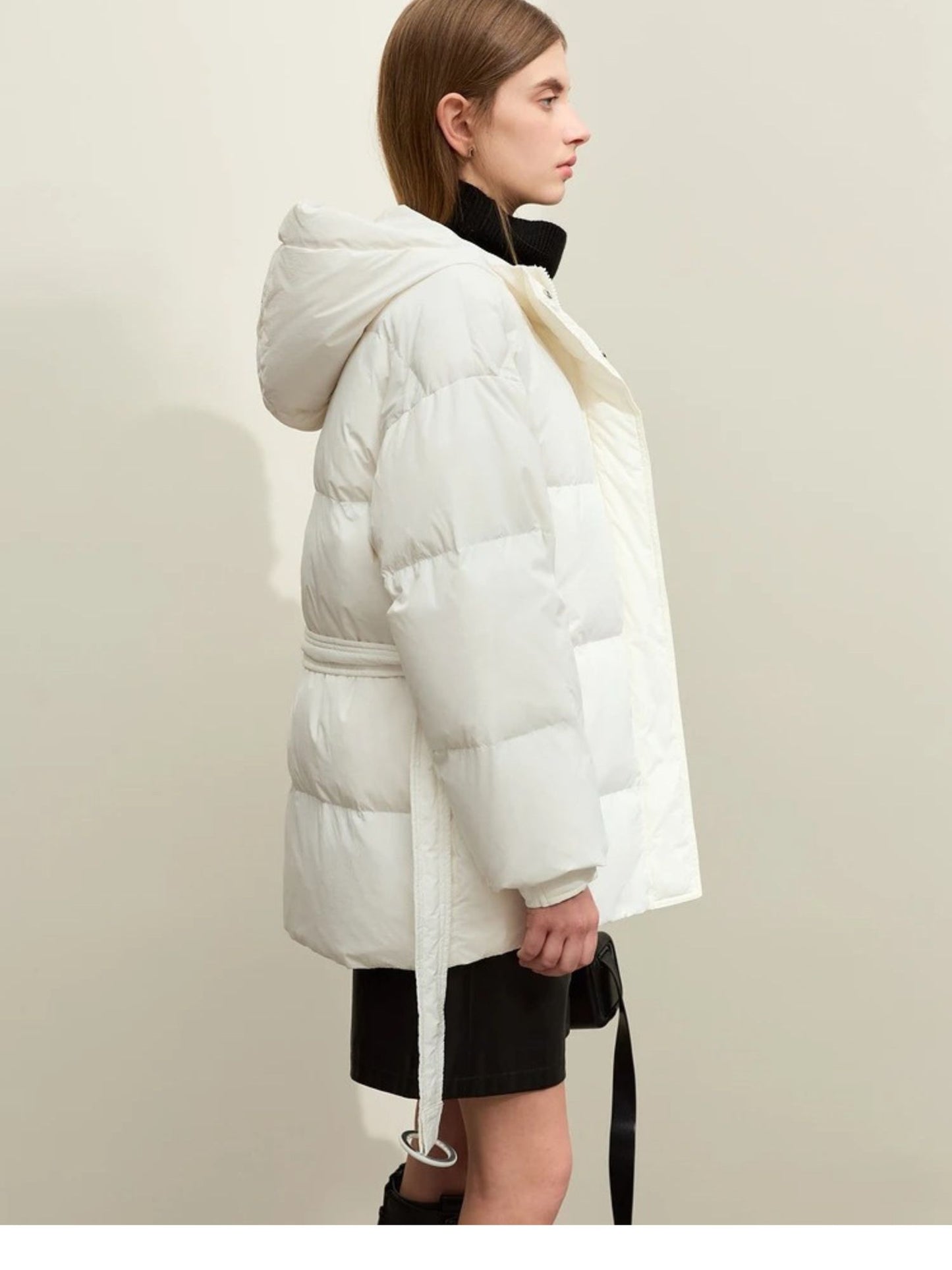 Side profile of the white puffer jacket. The model is looking forward with a slight head turn. The puffiness and hood are clearly defined