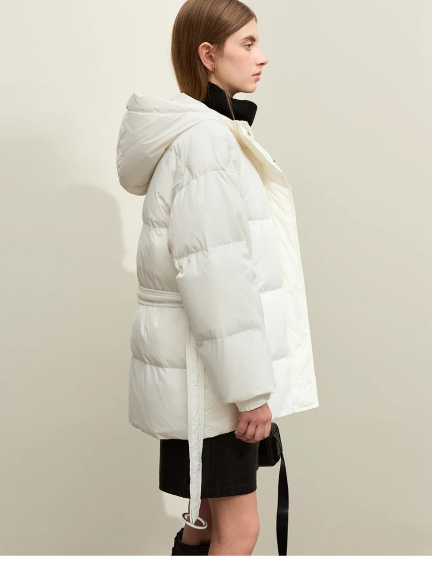 Side profile of the white puffer jacket. The model is looking forward with a slight head turn. The puffiness and hood are clearly defined