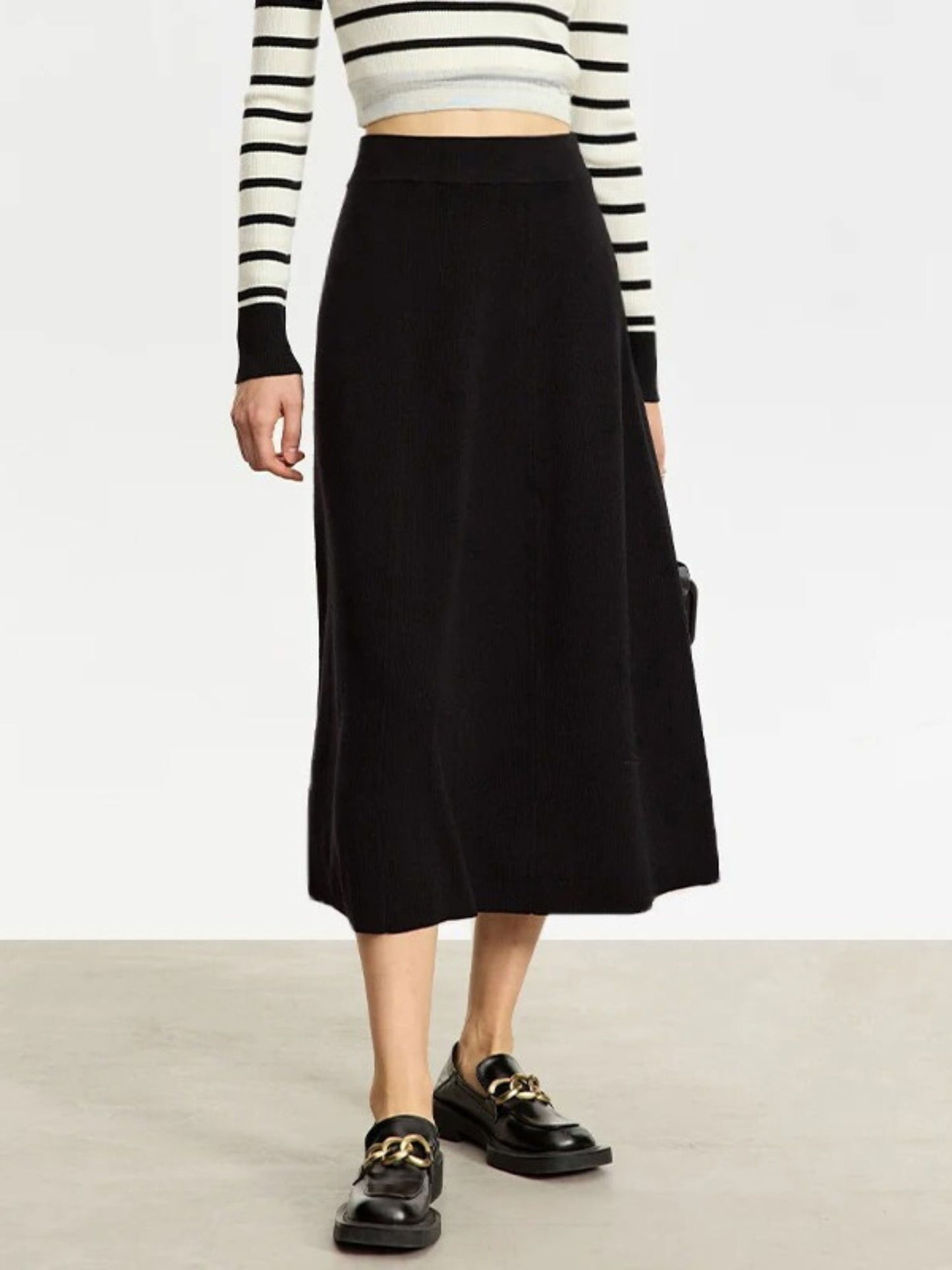 Person wearing a black skirt with a striped long-sleeve top on a plain background