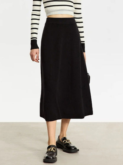 Person wearing a black skirt with a striped long-sleeve top on a plain background