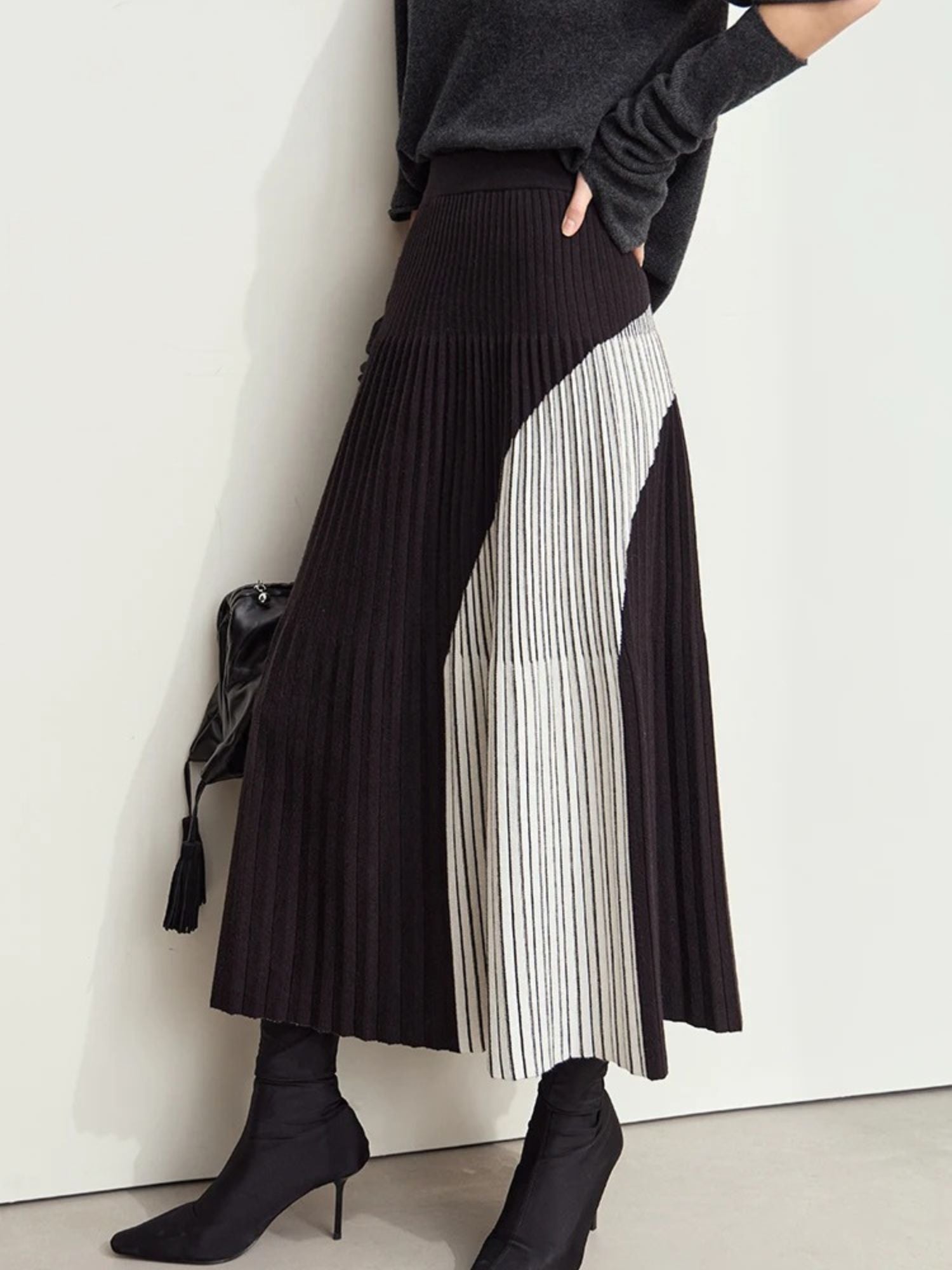 Back side view of black pleated midi skirt with light gray color-block panel