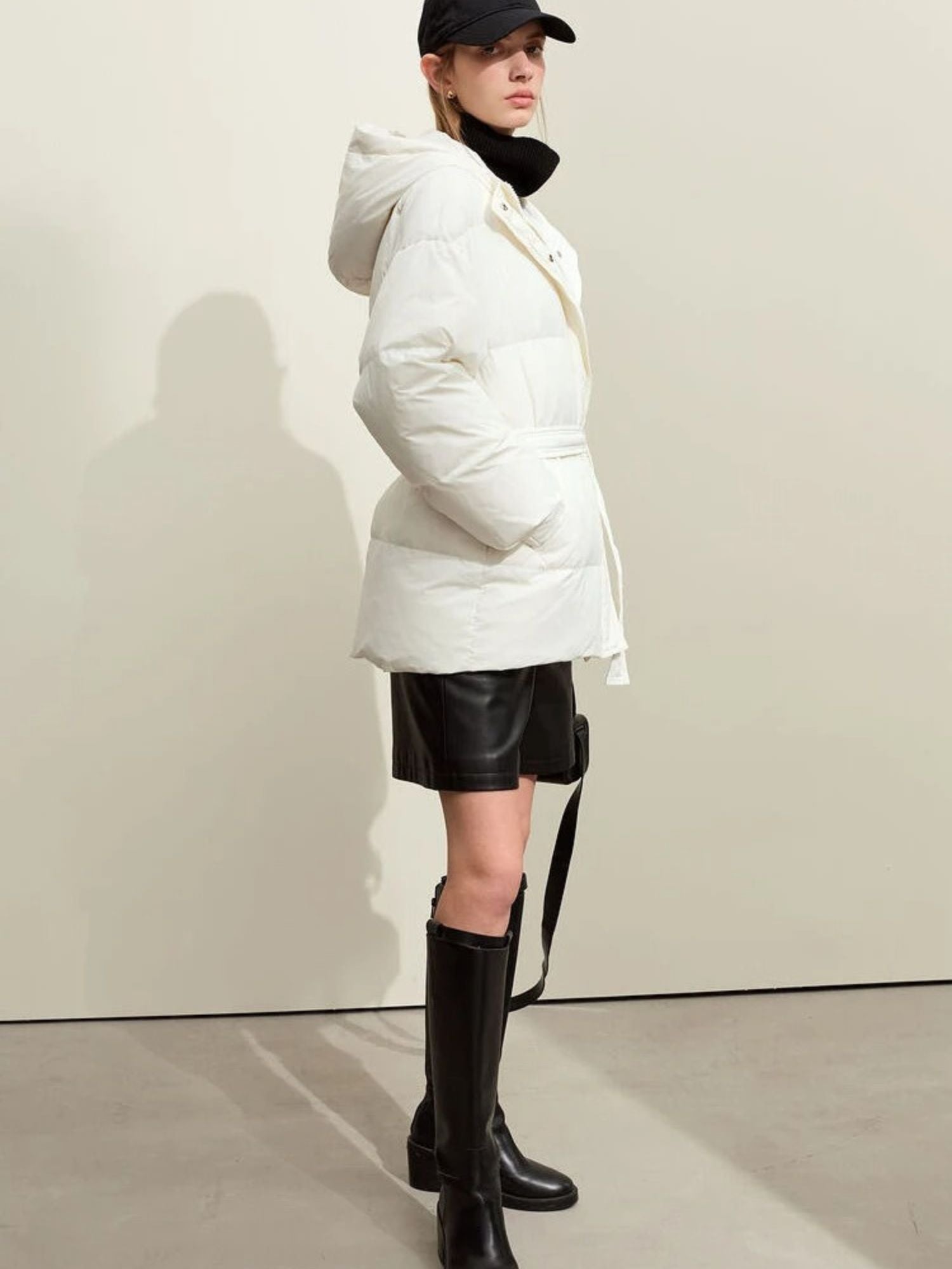 Back angle of the model in the white puffer jacket. The structure and belt at the waist are shown, and the hood is up