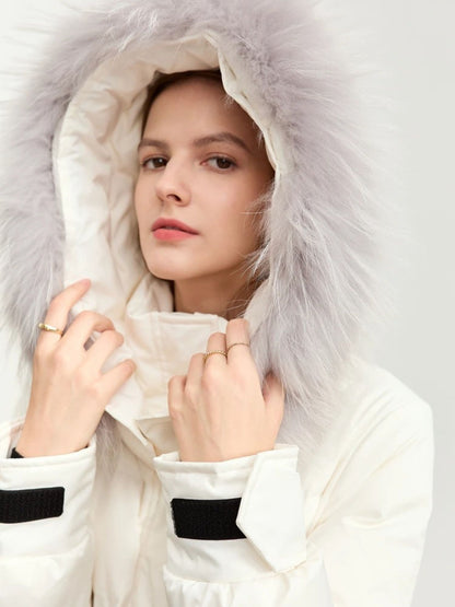 Close-up of the white coat's hood with fur trim. The model has her hands gently framing the hood, looking forward