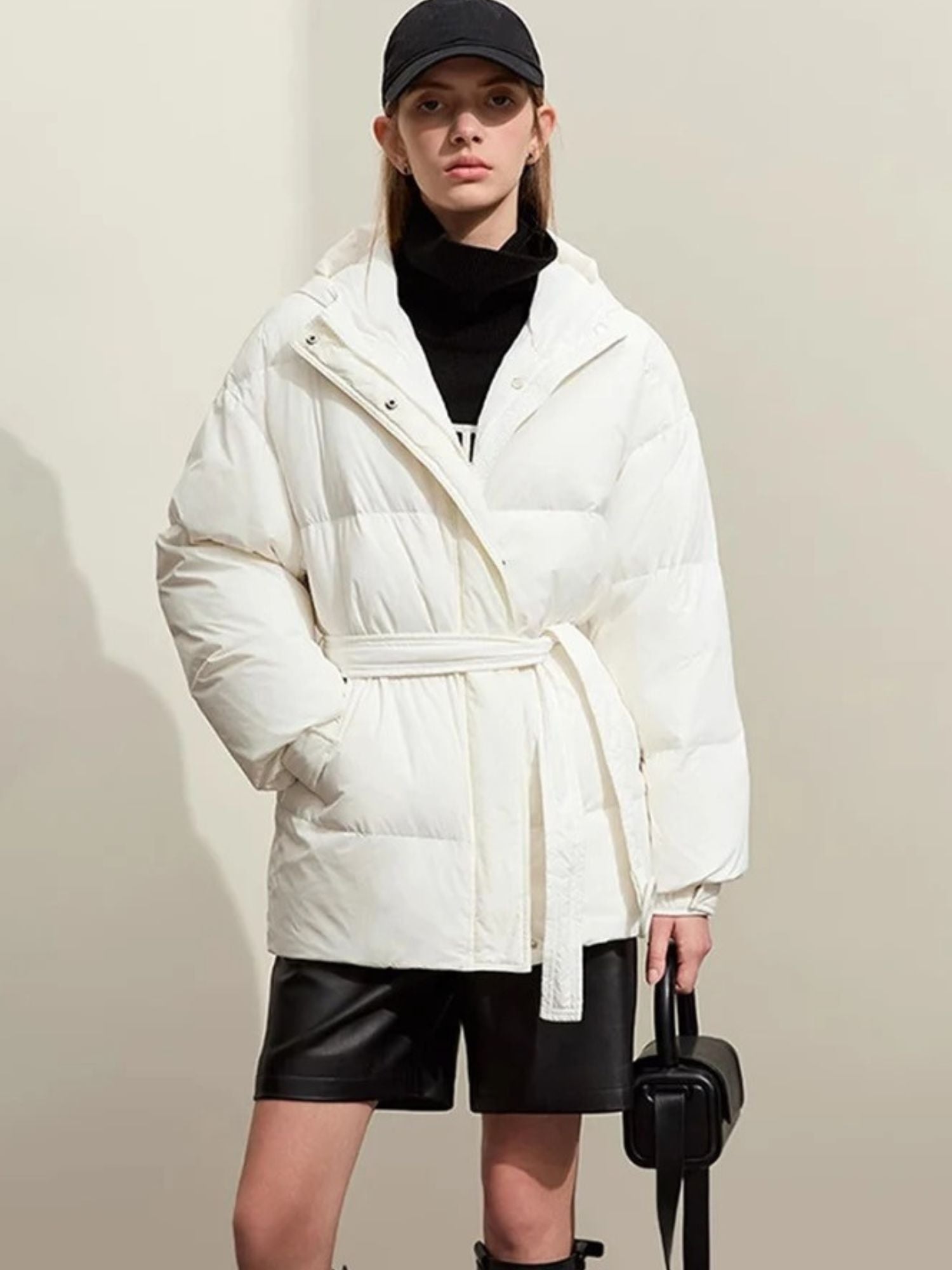 A slight three-quarter view of the white puffer. The model is standing naturally, highlighting the curved seams and fit of the jacket