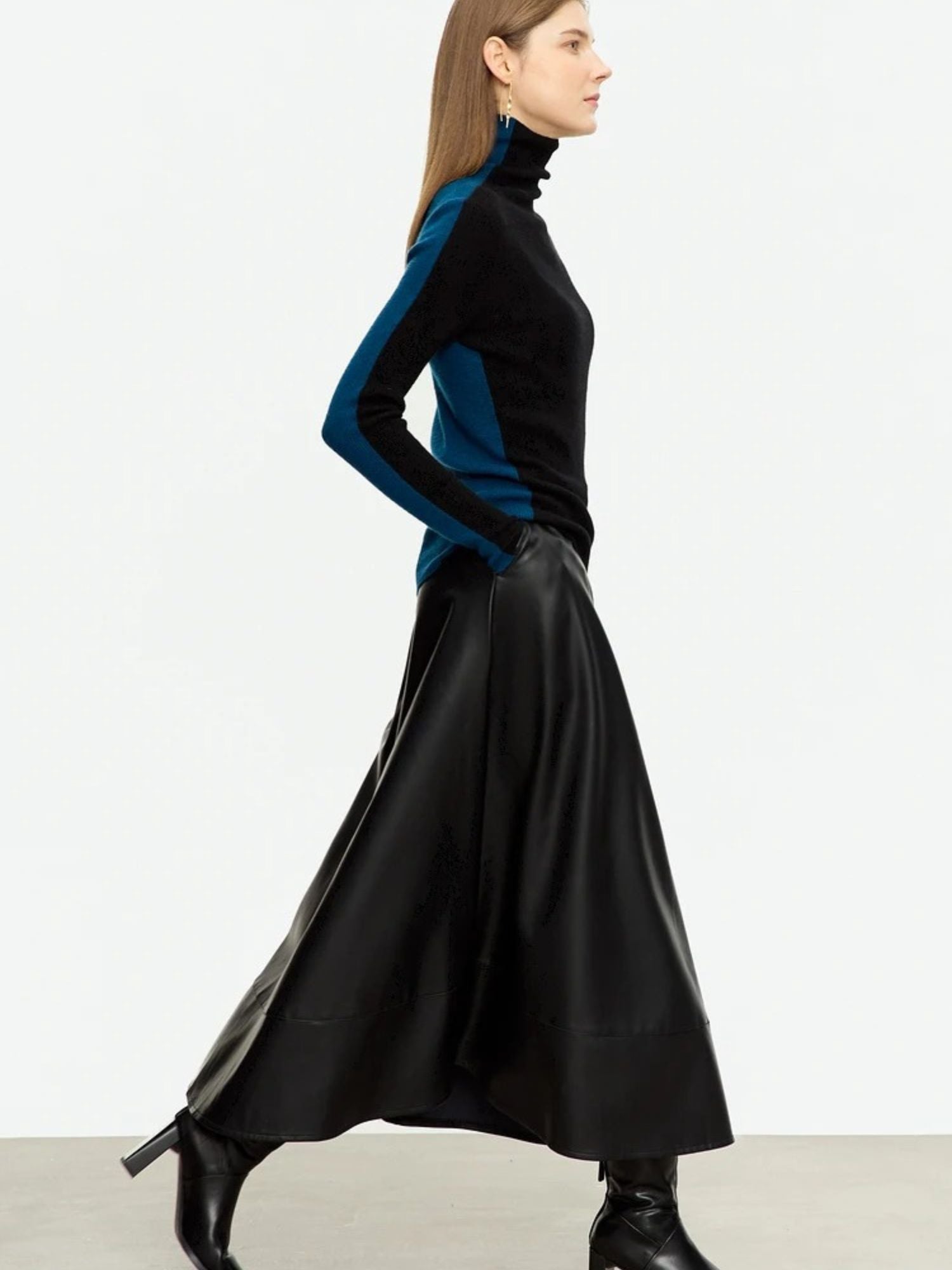 Side profile of woman in black midi leather skirt showing soft sheen and flowy silhouette
