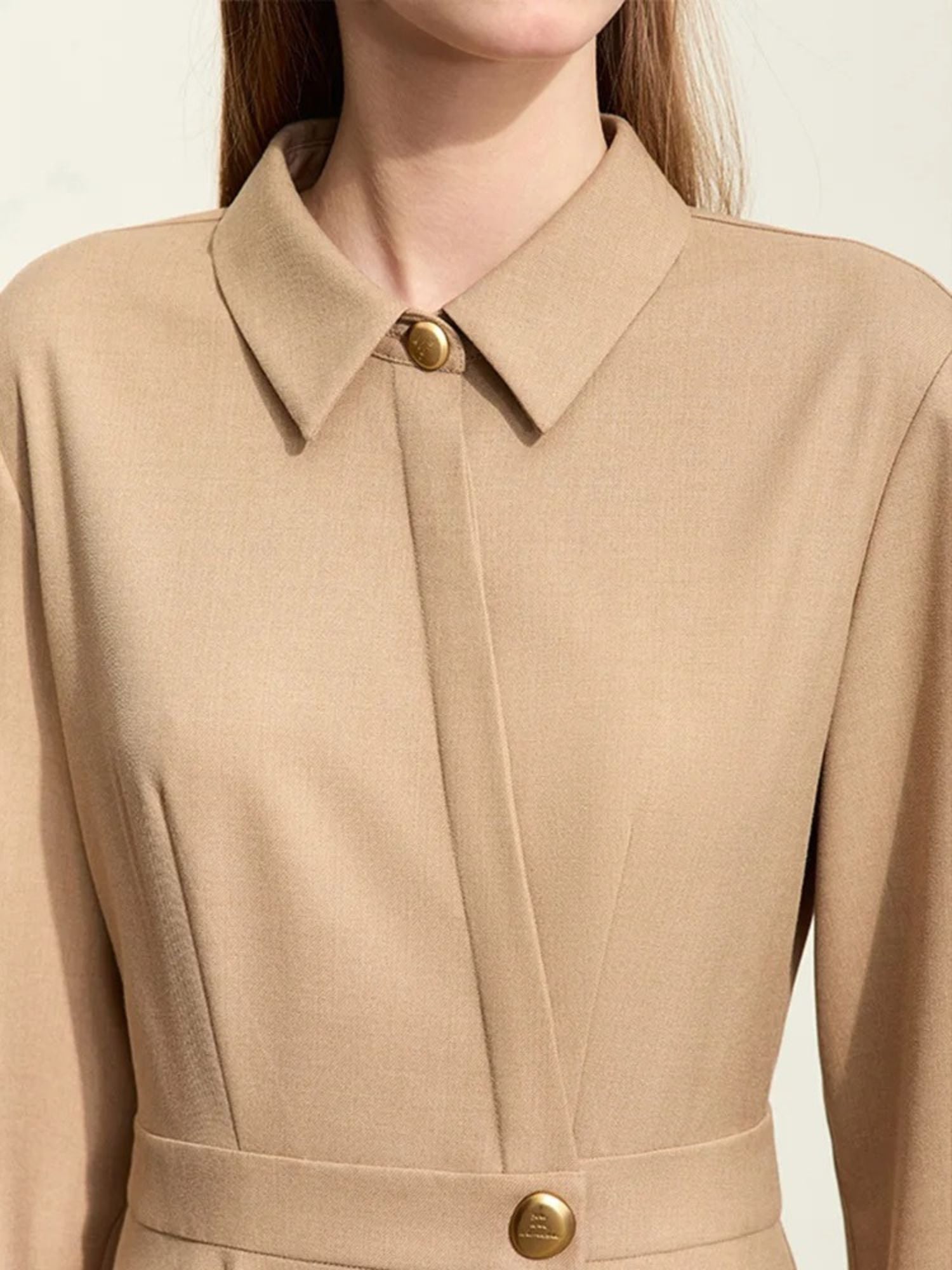 Close-up of camel dress bodice showing pleats, buttoned waist, and tailored collar
