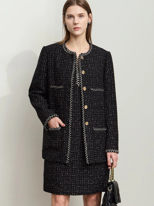 Model wearing black tweed boucle jacket with gold buttons and matching mini skirt, styled with handbag